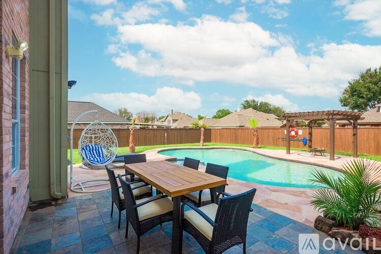 A patio with a table and chairs overlooking a pool.