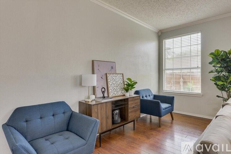 A living room with a blue chair and a wooden cabinet.