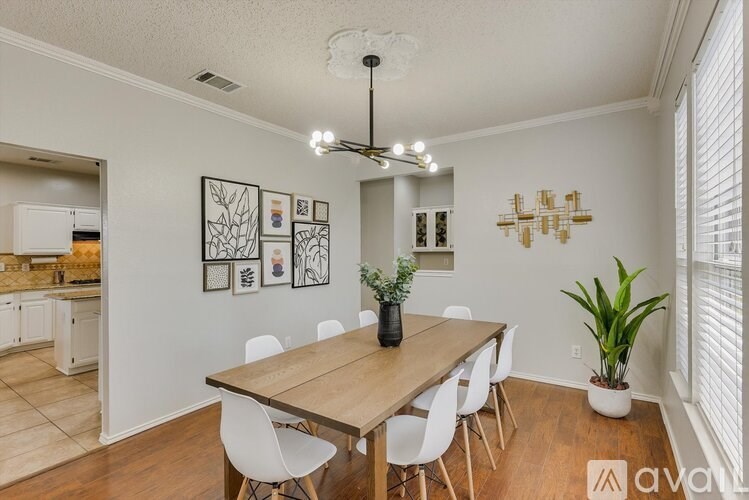 A dining room with a wooden table and white chairs.