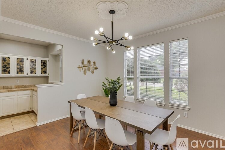 A dining room with a wooden table and white chairs.