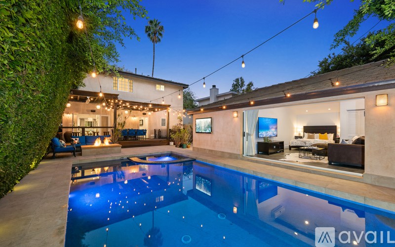 A pool in a backyard with lights strung above it.