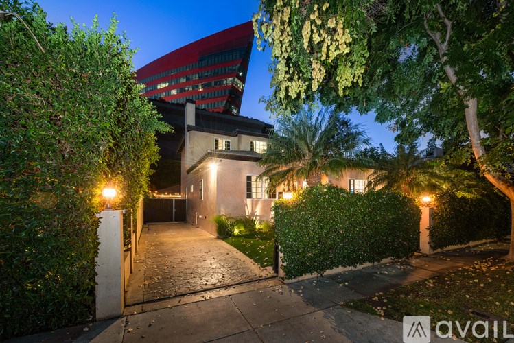 A house with a driveway and a tall building in the background.