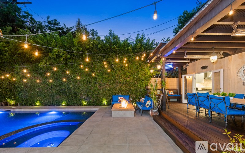 A poolside area with a lit string of lights and a blue lounge chair.