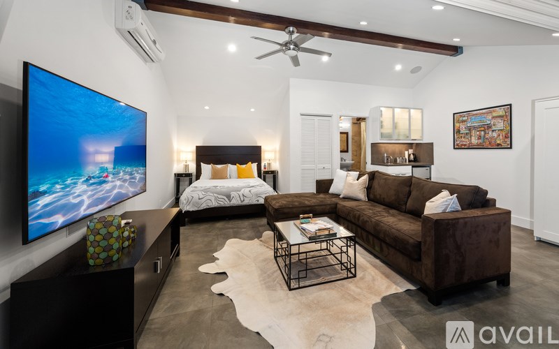 A modern living room with a large TV and a brown couch.
