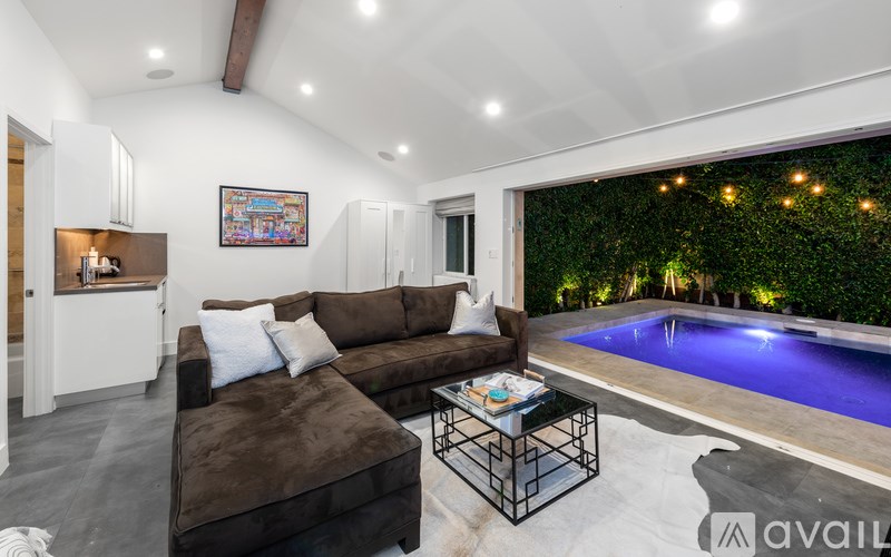 A living room with a brown couch and a pool outside.
