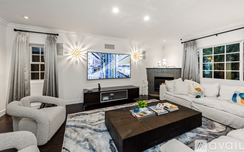 A modern living room with a large screen TV and comfortable seating.