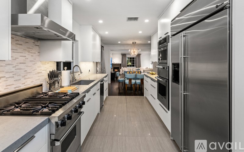 A modern kitchen with stainless steel appliances and a dining area in the background.