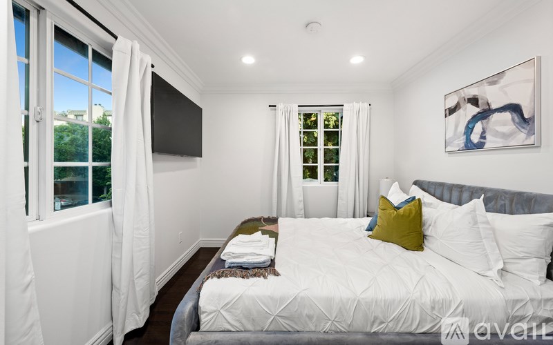 A bedroom with a large bed and a painting on the wall.