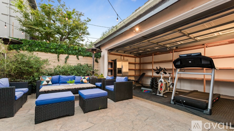 A patio with a black sofa, a blue cushion, and a treadmill.
