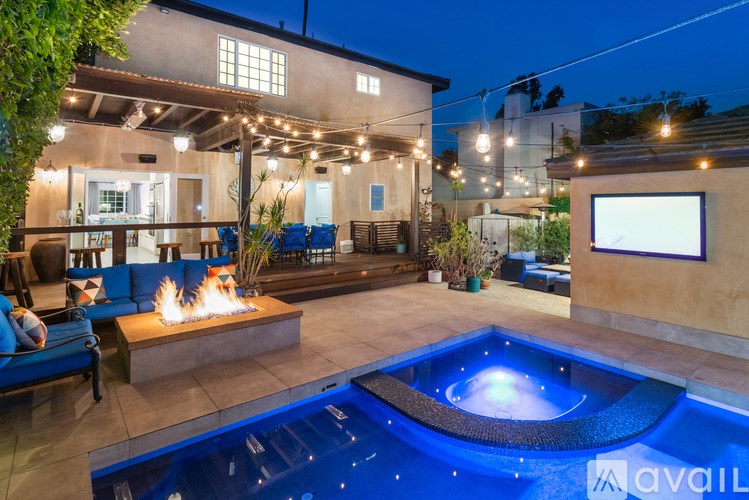 A modern house with a pool and a lit up fire pit.