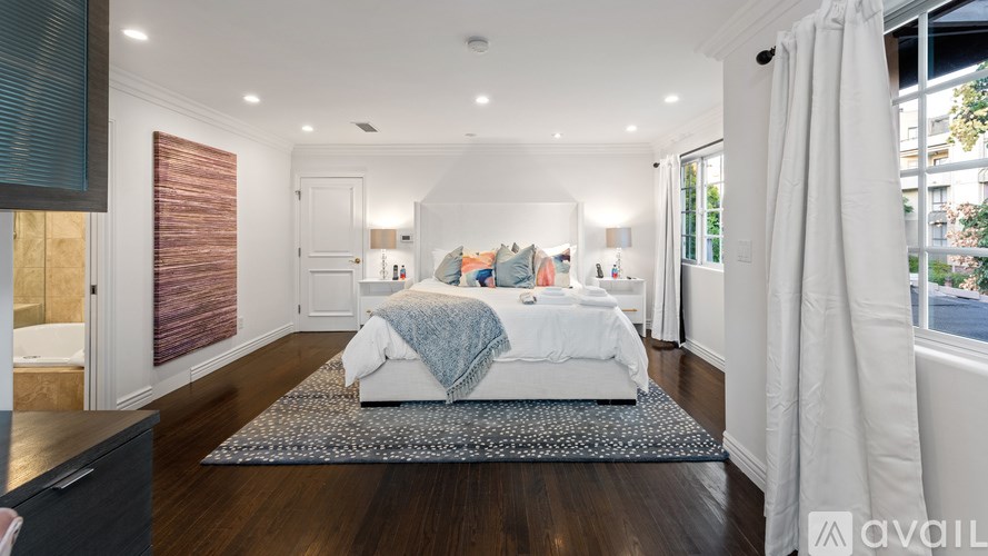 A bedroom with a bed, a dresser, and a window with blinds.