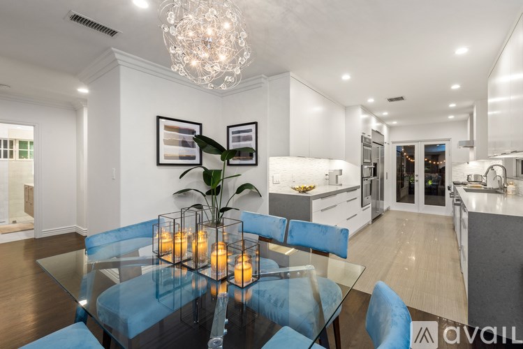 A modern dining room with a glass table and blue chairs.