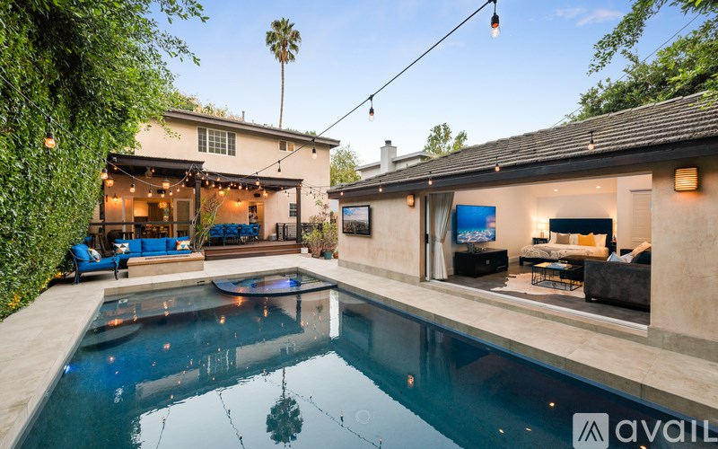 A pool in a backyard with a house and a tree in the background.