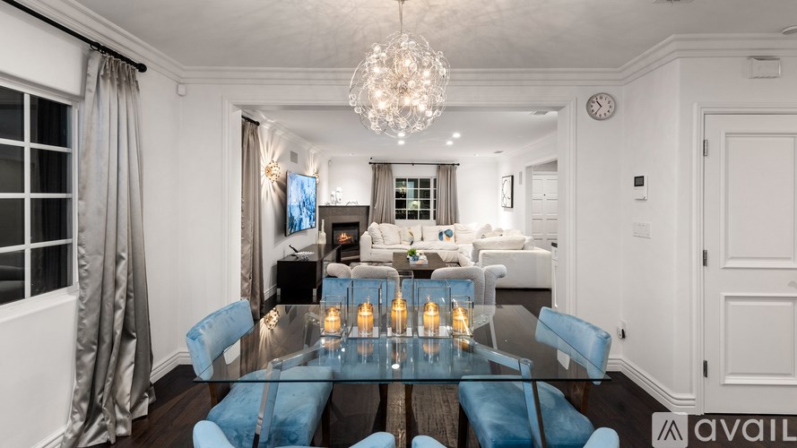 A dining room with a glass table and blue chairs.