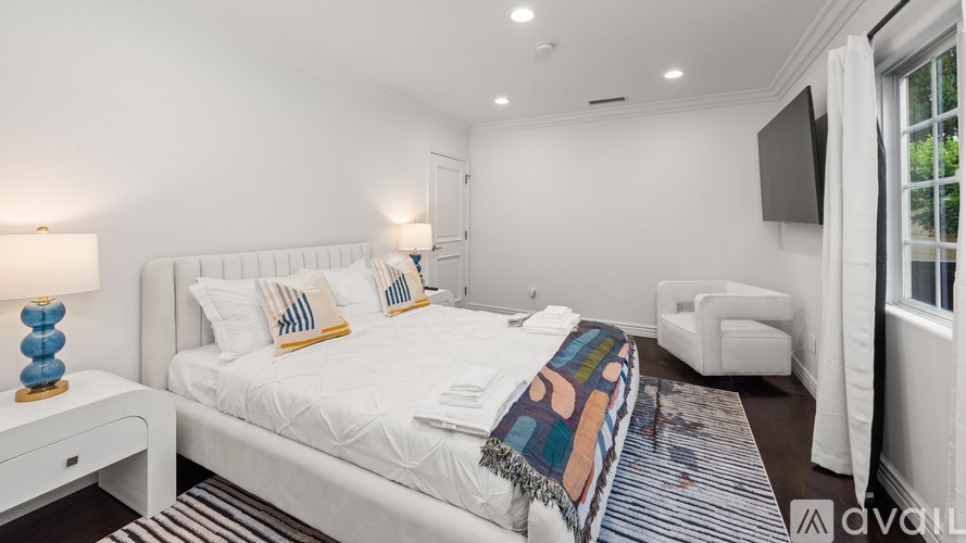 A bedroom with a large bed and a television on the wall.