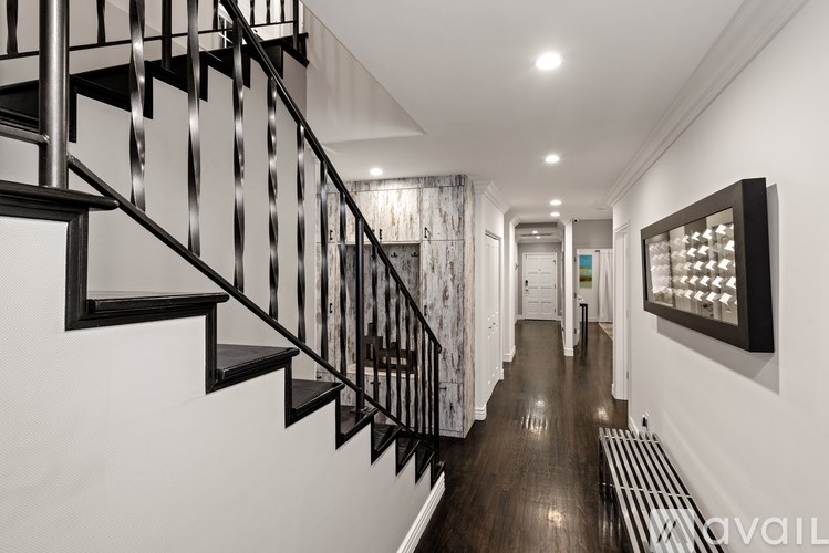 A long hallway with a staircase on the left and a picture on the right.