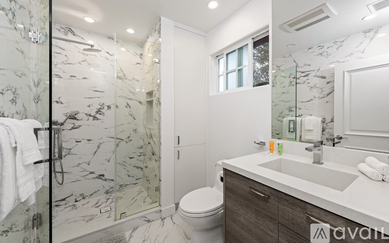 A bathroom with a marble patterned shower and a white toilet.
