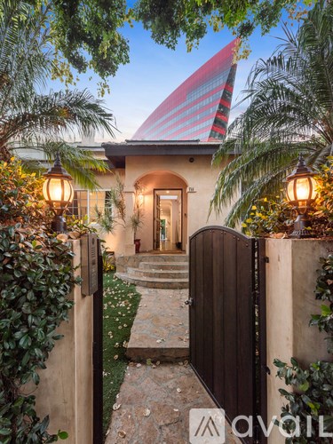 A house with a red and white striped roof is seen through a gate.