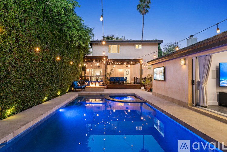 A pool with lights in the water and a house with lights on the outside.