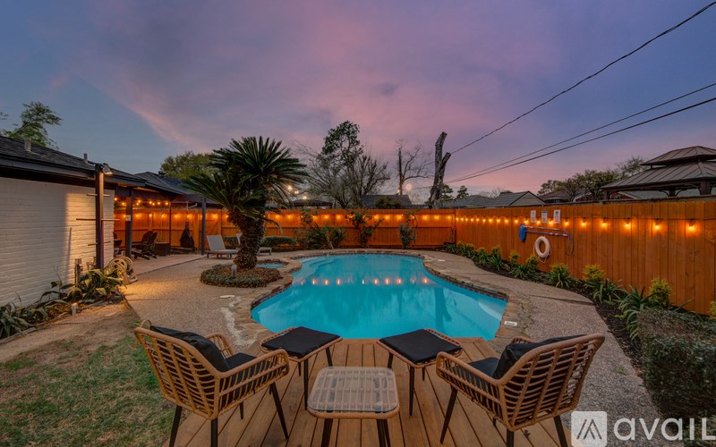 A pool surrounded by chairs and string lights.