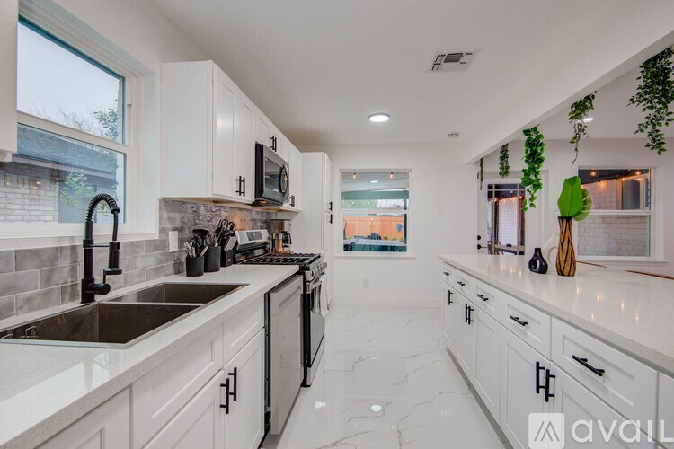 A kitchen with white cabinets and a marble countertop.