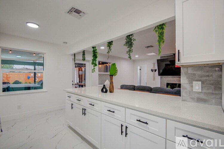 A kitchen with white cabinets and a marble countertop.