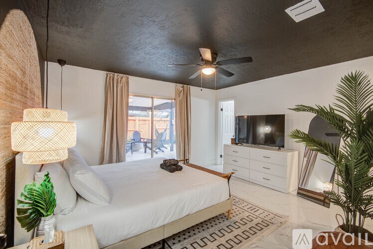 A bedroom with a large bed, a ceiling fan, and a television.
