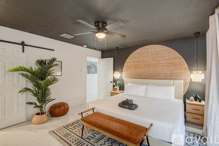 A bedroom with a bed, a bench, and a plant.