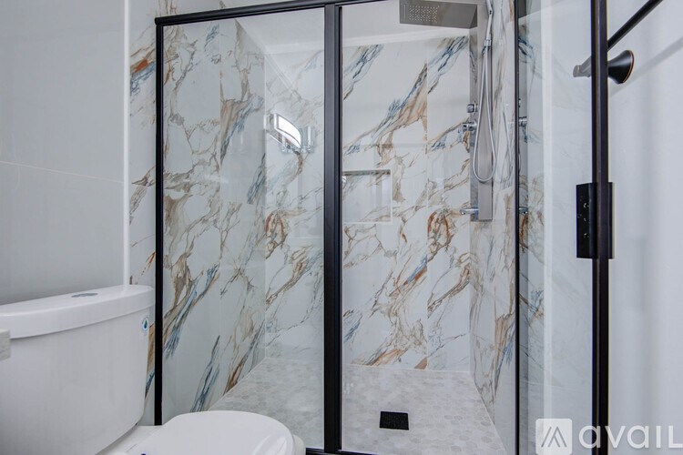 A bathroom with a marble patterned shower.