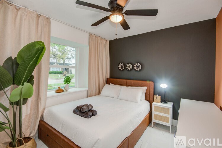 A bedroom with a large bed, a ceiling fan, and a potted plant.