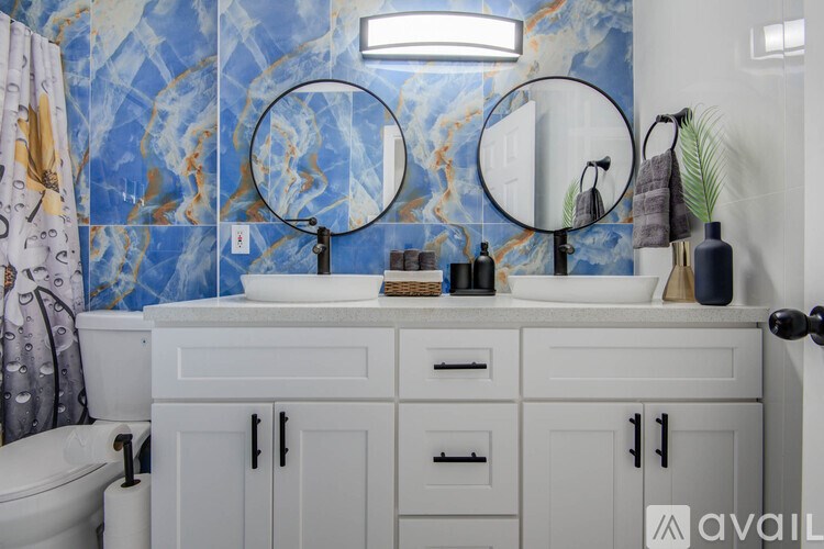 A bathroom with a white vanity and a blue patterned wallpaper.