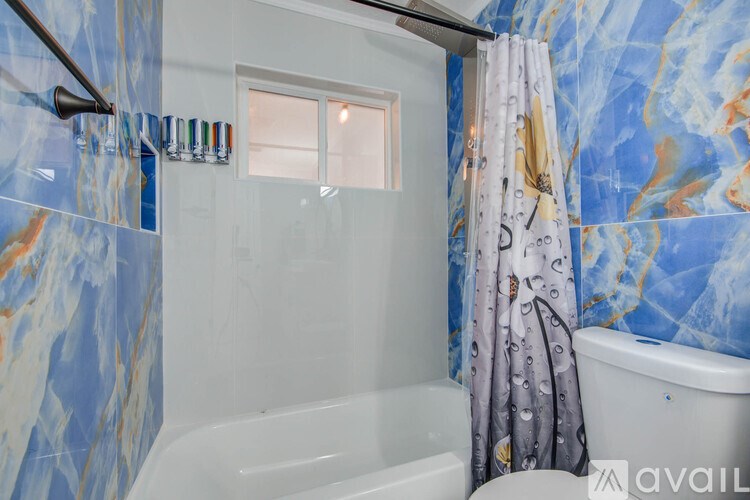 A bathroom with a blue and white tiled wall and a white bathtub.