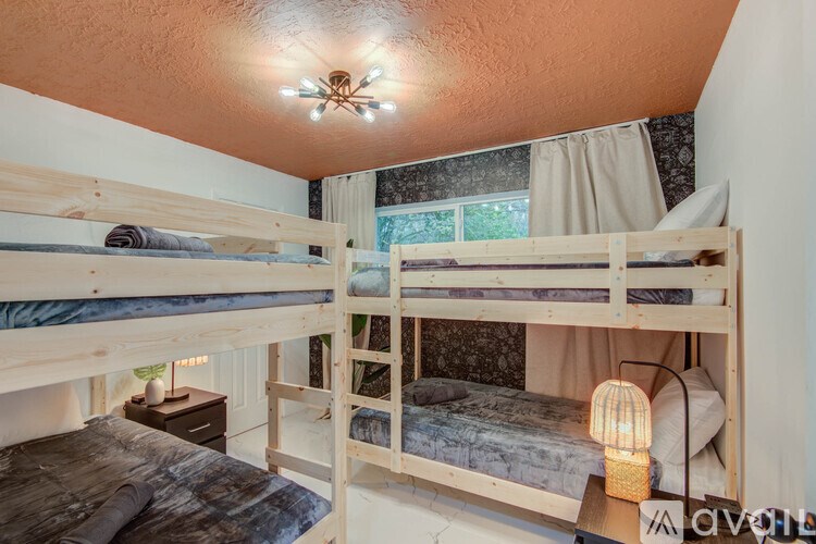 A room with bunk beds and a table with a lamp on it.