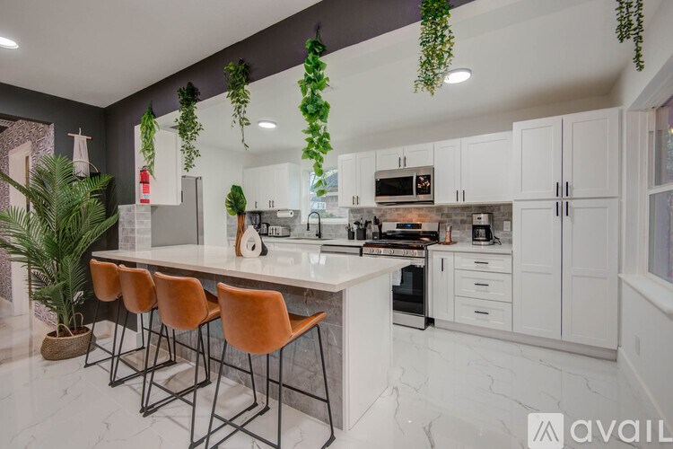 A kitchen with a white countertop and orange chairs.