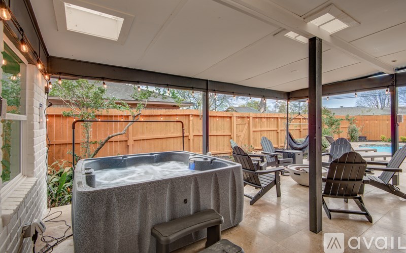 A hot tub is in the middle of a patio with chairs around it.