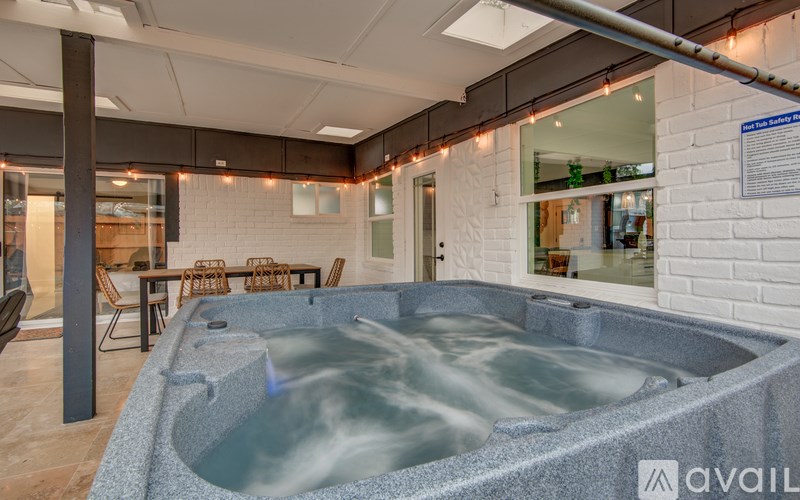 A hot tub in a room with a white brick wall and string lights.
