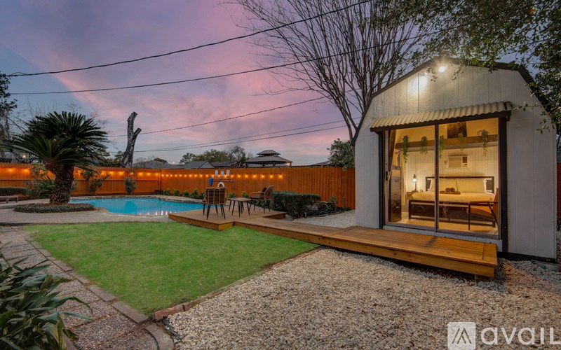 A backyard with a pool and a house with a patio.