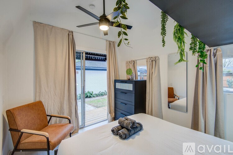 A bedroom with a bed, chair, and plants.