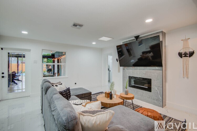 A living room with a grey couch and a fireplace.