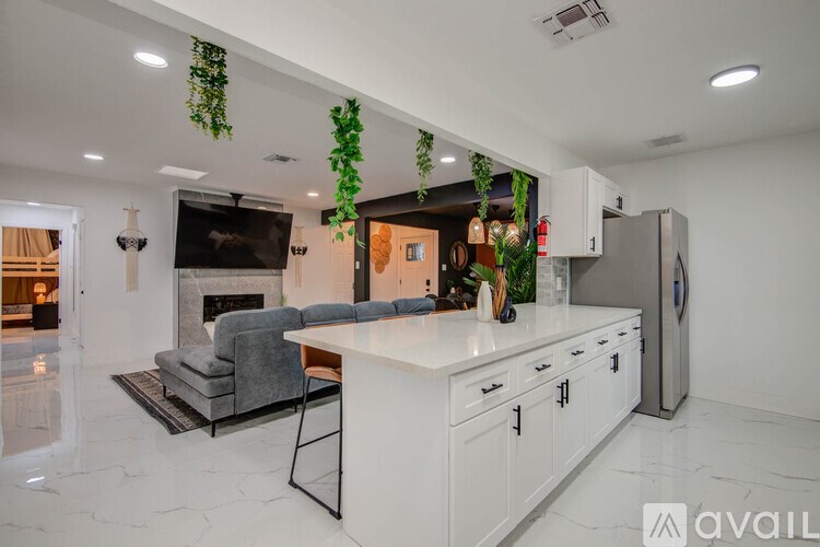 A modern kitchen with a white countertop and grey chairs.