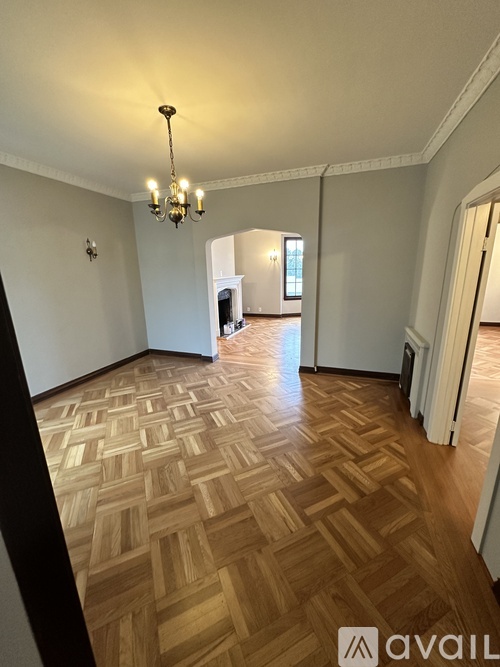 A room with wooden flooring and a chandelier.