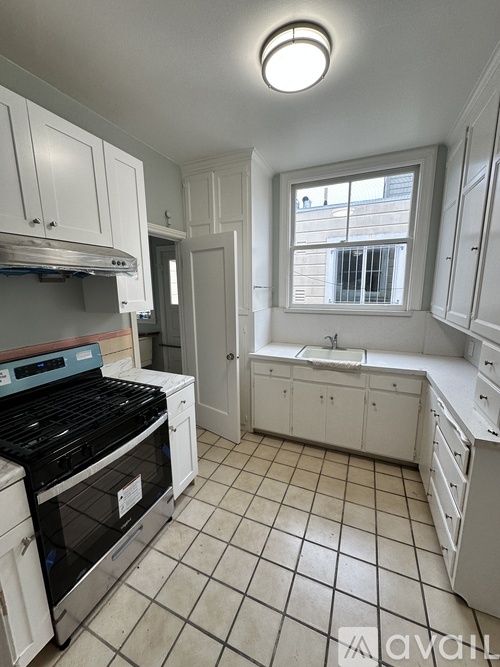 A kitchen with white cabinets and a black stove top oven.