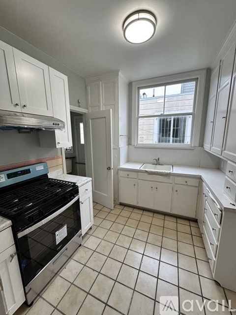 A kitchen with white cabinets and a black stove top oven.