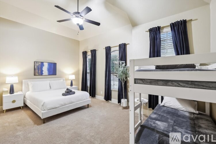 A bedroom with a white bed and a bunk bed with a ceiling fan.