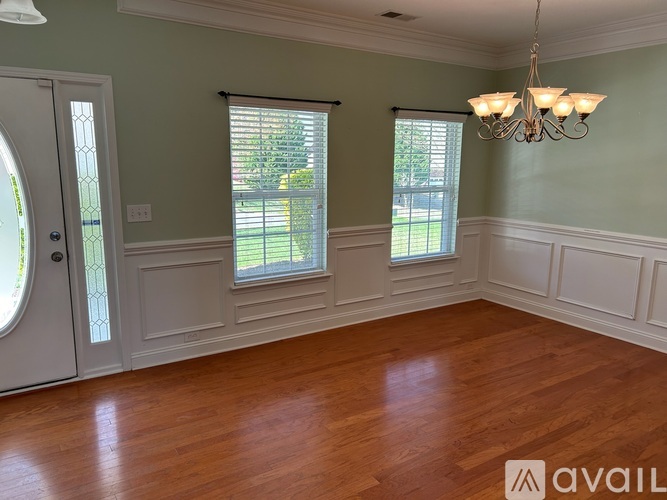 A room with wooden floors and a chandelier hanging from the ceiling.