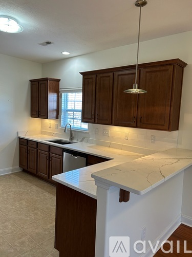 A kitchen with white countertops and wooden cabinets.