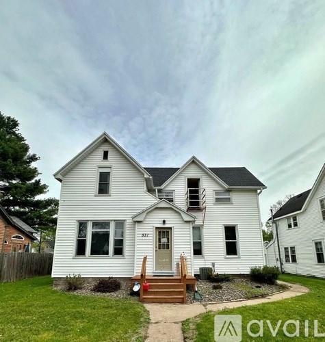 A white house with a grey roof and a wooden front porch.