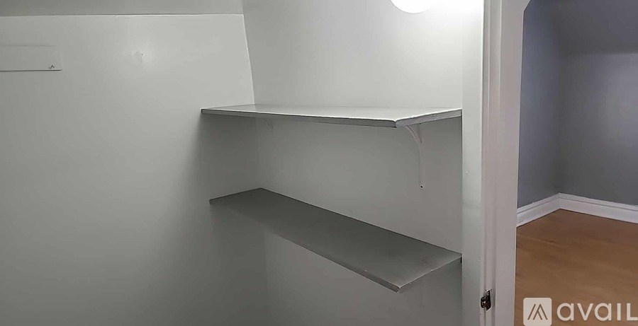 A white shelf in a room with a light on.