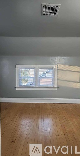 A room with a window and wooden flooring.
