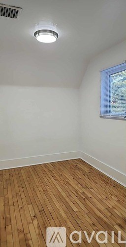 A room with wooden flooring and a window with blinds.